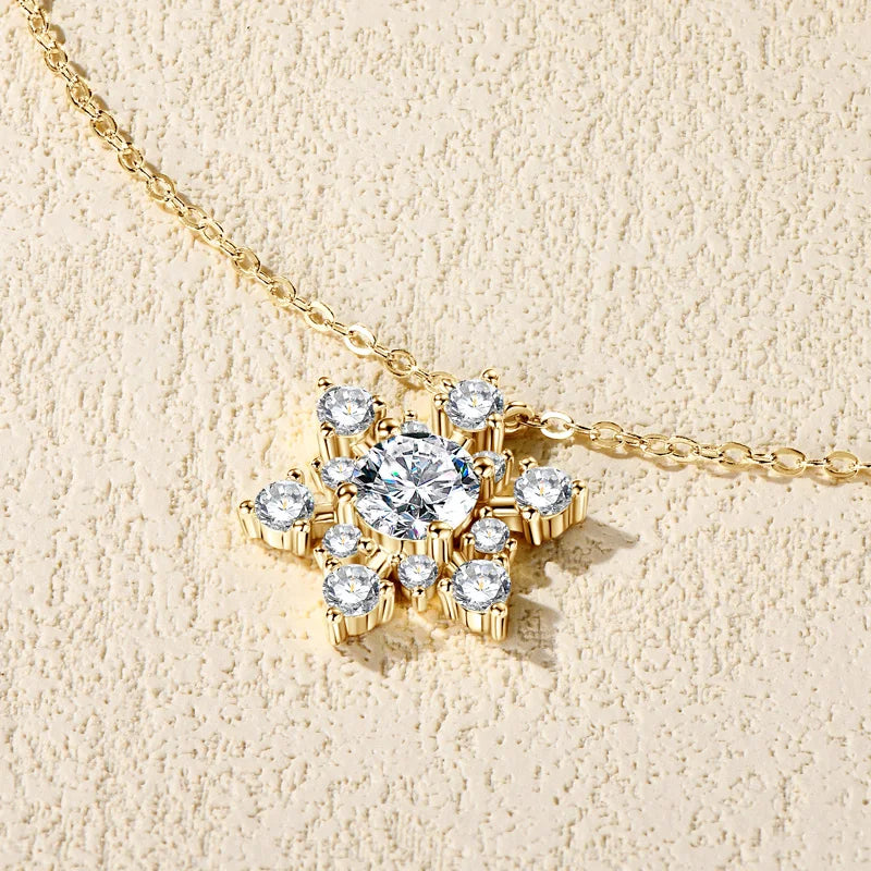 Gold necklace with a snowflake-shaped pendant on a beige background