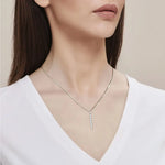 Woman wearing a delicate necklace with a neutral background