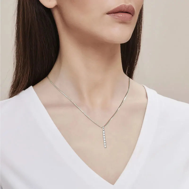 Woman wearing a delicate necklace with a neutral background