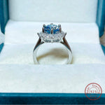 Silver ring with a blue gemstone on a white cushion, brand 'Real Sterling' visible.