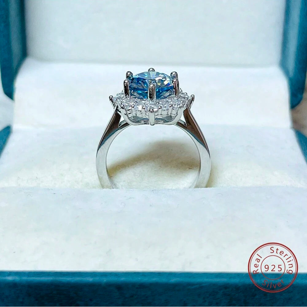 Silver ring with a blue gemstone on a white cushion, brand 'Real Sterling' visible.