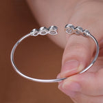 Silver ring with three small stones held by a hand against a brown background