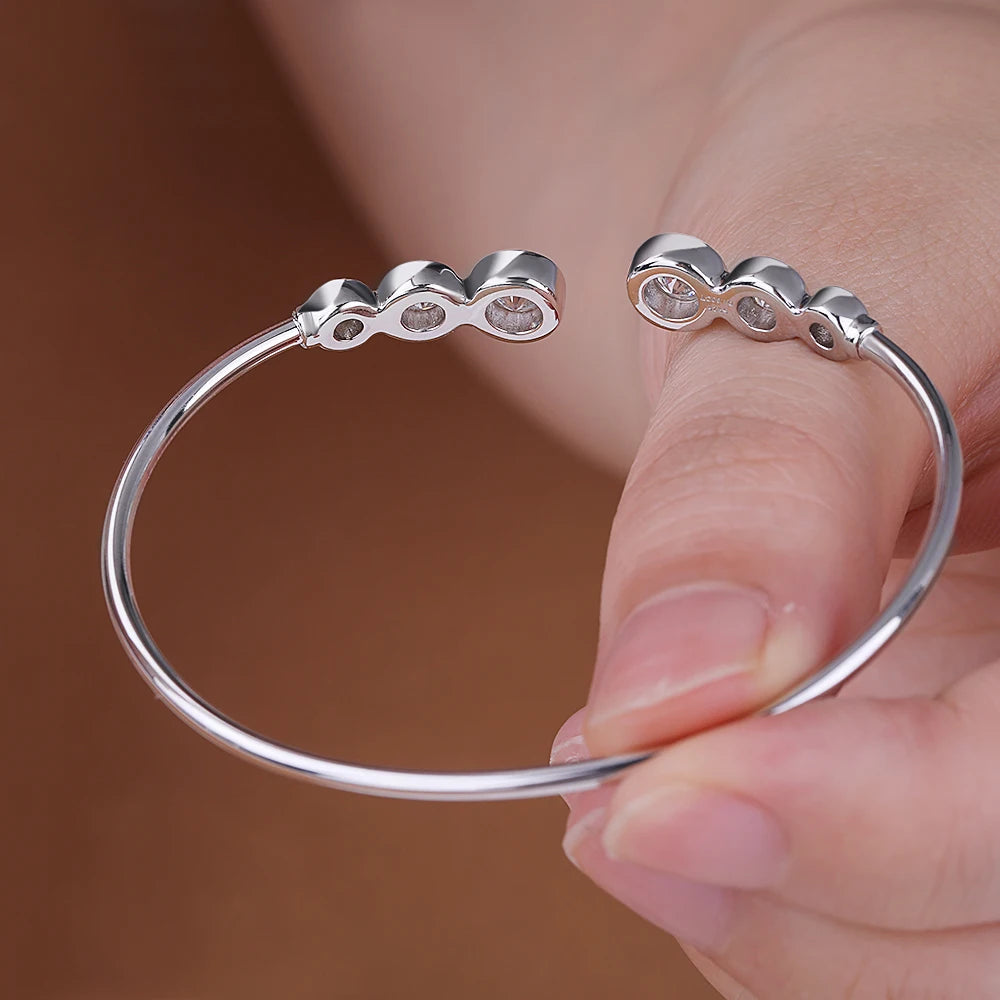 Silver ring with three small stones held by a hand against a brown background