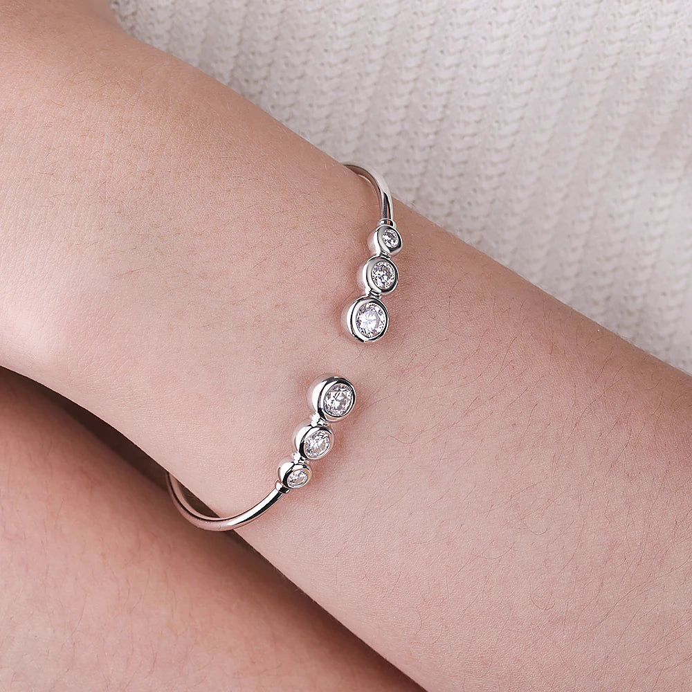 Silver bracelet with clear stones on a wrist against a neutral background