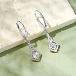 Silver earrings with gemstones on a light stone and green fabric background