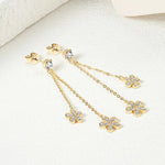 Gold earrings with chain and clover designs on a white background
