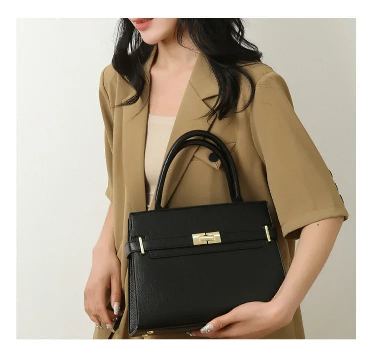 Person holding a black handbag with a neutral background