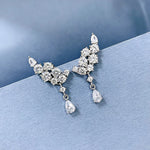 Pair of silver earrings with clear gemstones on a blue background
