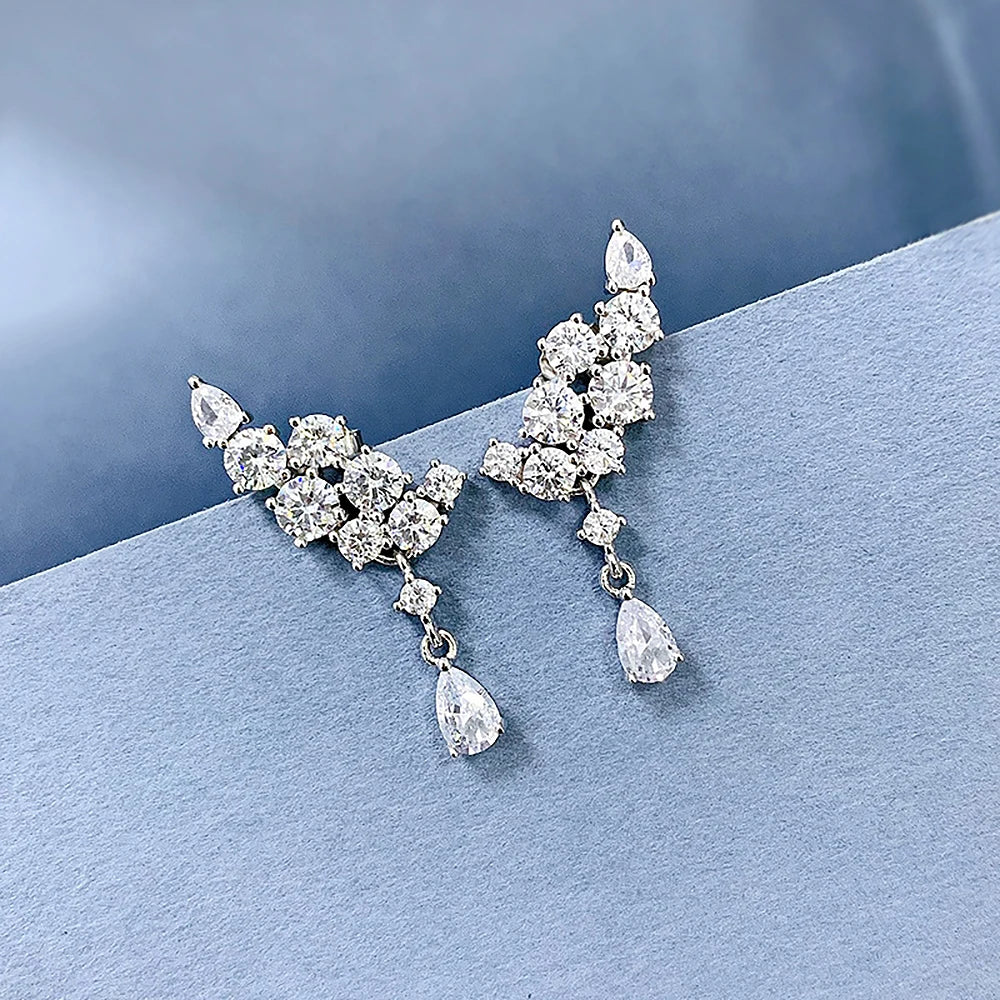 Pair of silver earrings with clear gemstones on a blue background