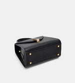 Black handbag with gold accents on a light gray background