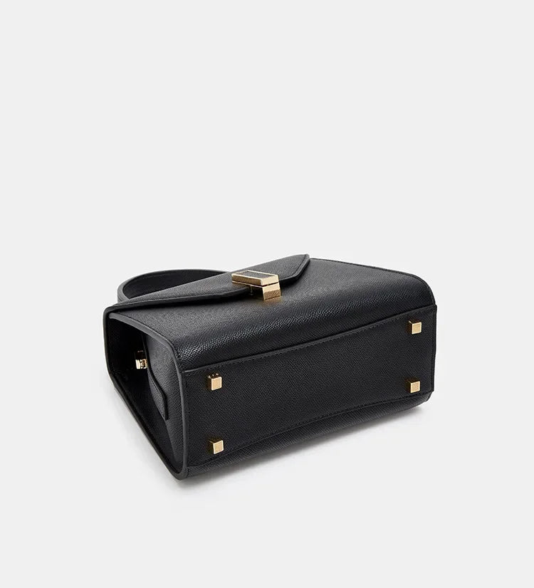 Black handbag with gold accents on a light gray background