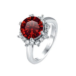 Silver ring with a red gemstone and small diamonds on a white background
