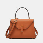 Brown leather handbag with gold buckle on a light gray background