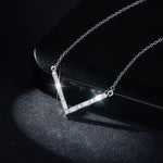 Silver necklace with a V-shaped pendant on a dark background