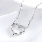 Silver heart-shaped necklace on a white fabric background