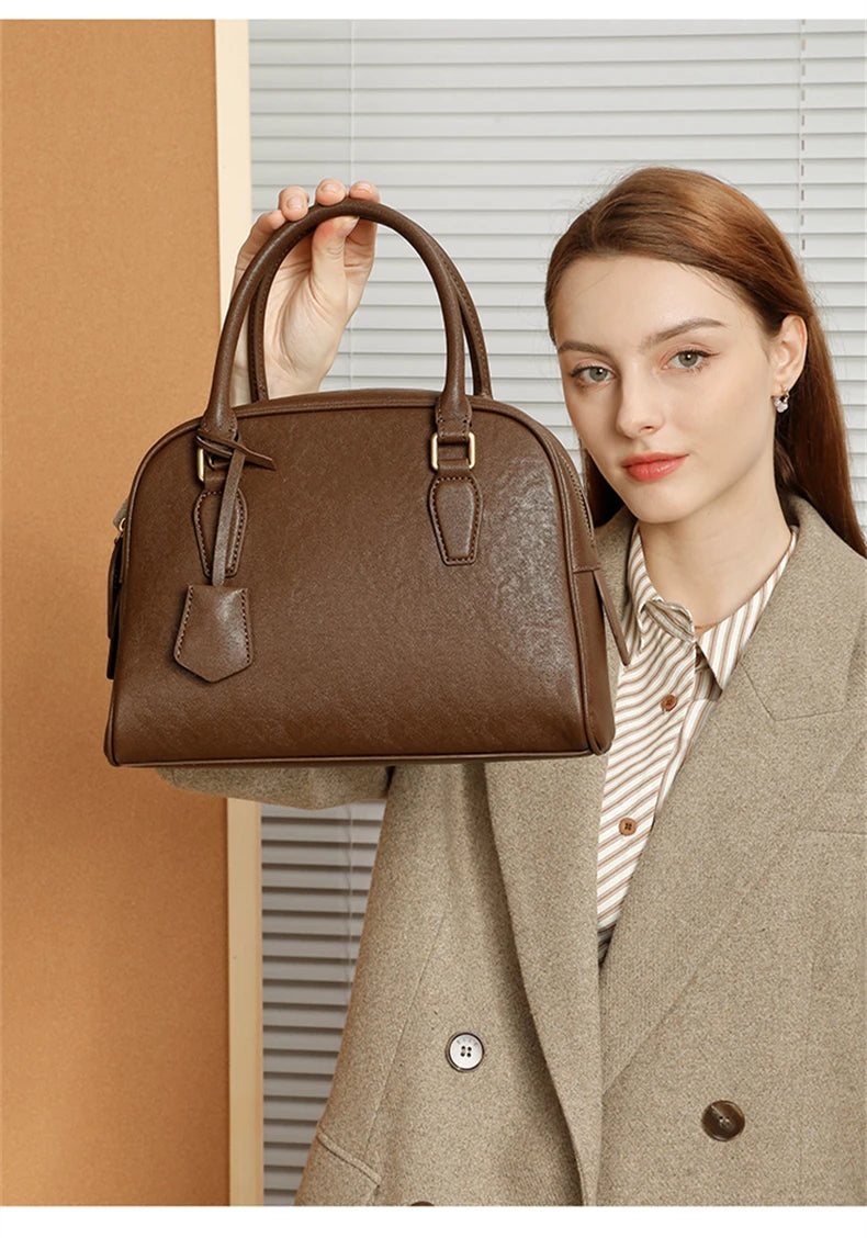 Woman holding a brown handbag against a neutral background