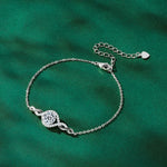 Silver bracelet with a decorative clasp on a green background