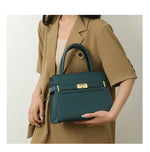 Person holding a teal handbag with a beige background