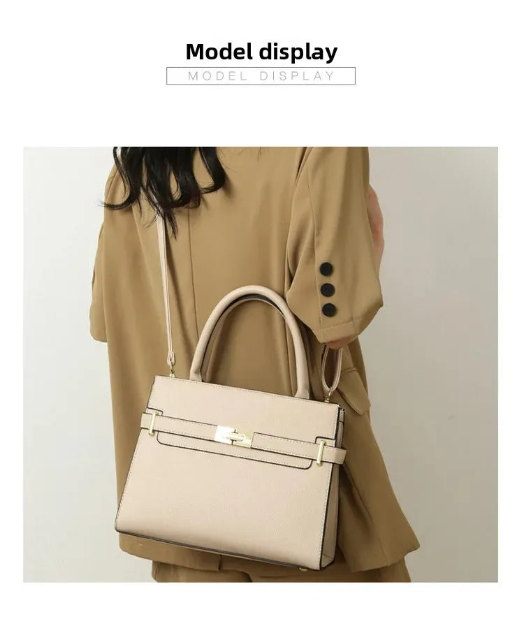 Beige handbag held by a person wearing a beige coat on a plain background