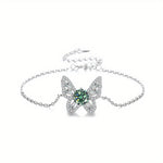 Butterfly-shaped bracelet with green gemstone on a white background