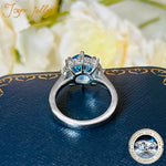 Silver ring with blue gemstone on a textured surface with floral background
