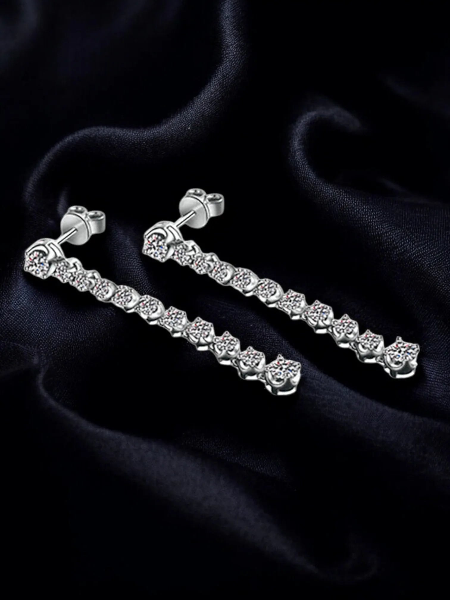 Silver earring set on a dark fabric background