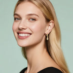 Woman wearing gold earrings with a light green background