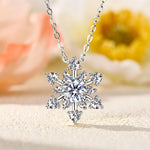Silver snowflake pendant necklace on a blurred floral background