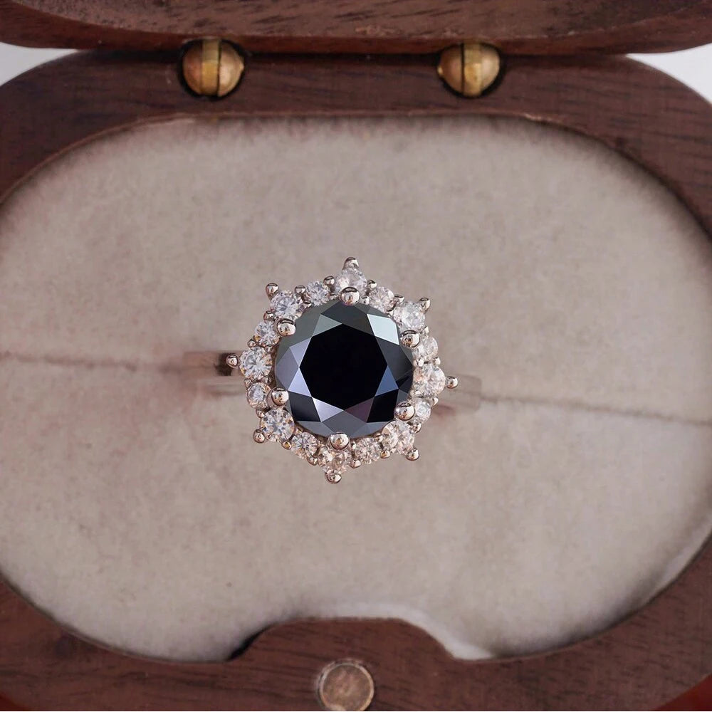Ring with a black gemstone and diamond halo in a wooden box