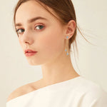 Close-up of a woman wearing elegant earrings with a plain background