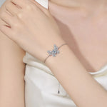 Silver bracelet with a starfish design on a person's wrist against a neutral background