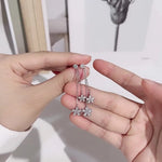 Person holding a pair of silver floral earrings with a blurred background
