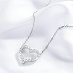 Silver heart-shaped necklace with clear stones on a white fabric background