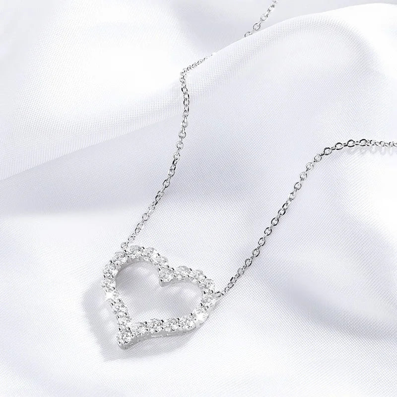 Silver heart-shaped necklace with clear stones on a white fabric background