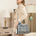 Woman holding a patterned handbag in a room with lamps and furniture.