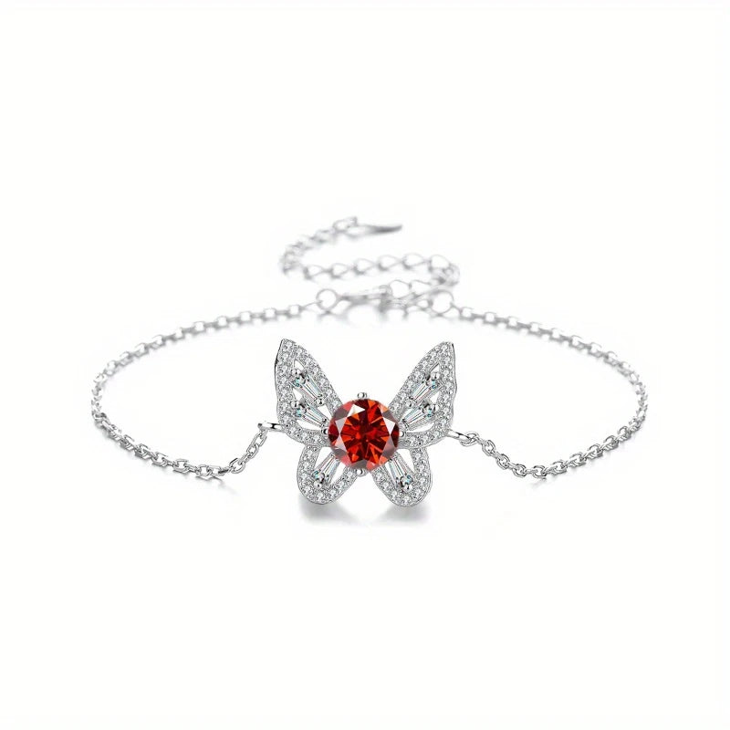 Butterfly-shaped bracelet with a red gemstone on a white background