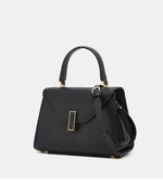 Black handbag with gold accents on a light gray background