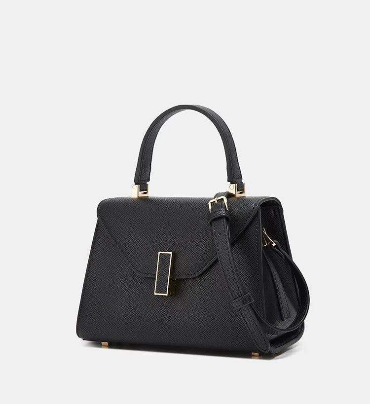 Black handbag with gold accents on a light gray background