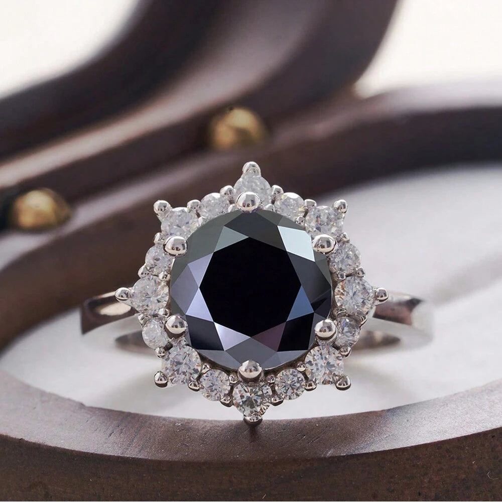 Ring with a central black gemstone and diamond-studded halo on a wooden surface