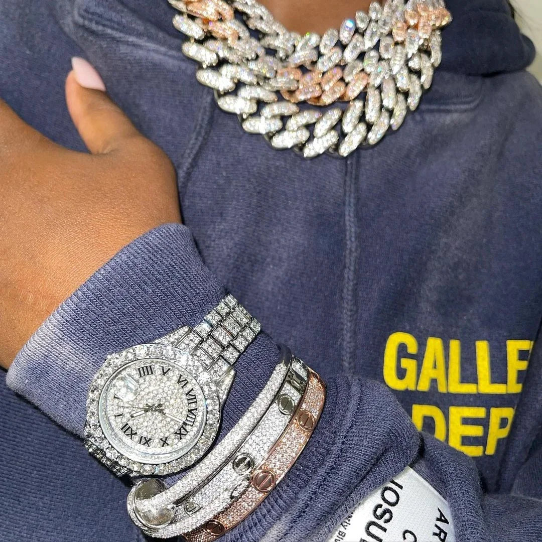 Person wearing a blue hoodie with 'Galle' text, multiple diamond-encrusted bracelets, and a watch.
