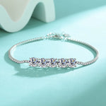 Silver bracelet with three clear gemstones on a light blue background