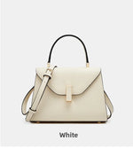 White handbag with gold accents on a light gray background