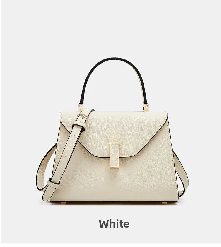 White handbag with gold accents on a light gray background
