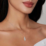 Close-up of a woman wearing a silver necklace with a leaf-shaped pendant.