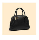 Black handbag with gold accents on a beige background