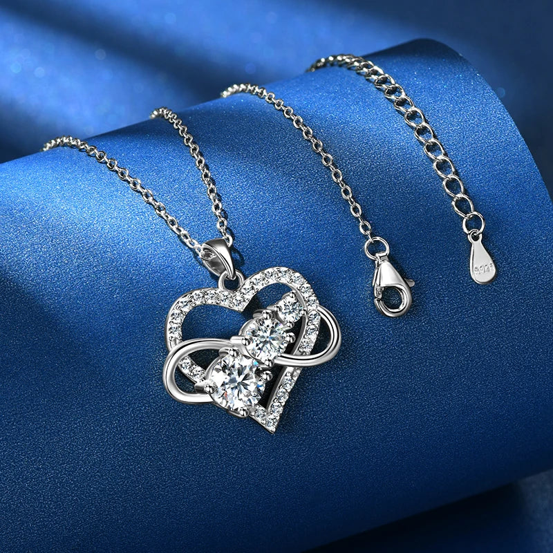 Silver heart-shaped necklace with a clasp on a blue fabric background