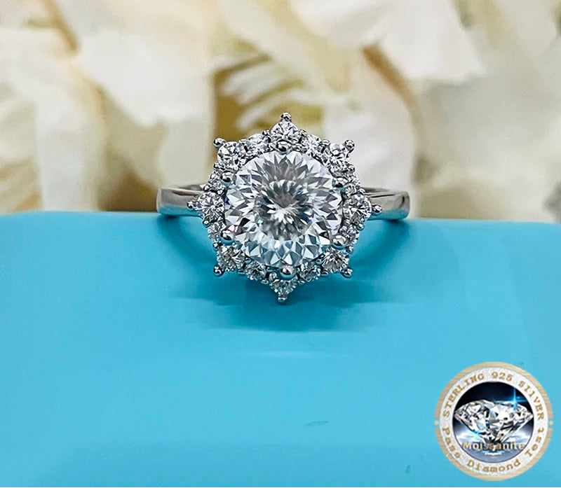 Silver ring with a large diamond on a blue surface, featuring the brand 'Joyce Jelly'.