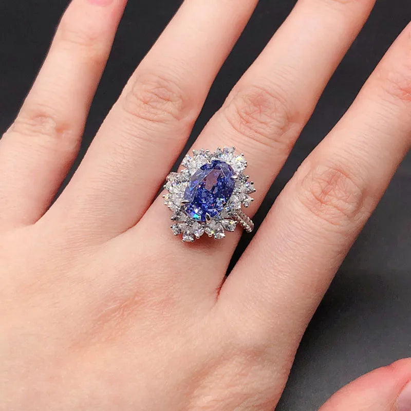 Ring with a blue gemstone on a person's finger against a dark background