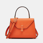 Orange handbag with a strap on a light gray background