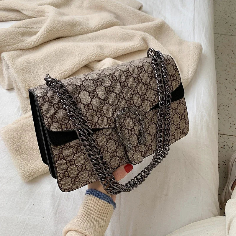 Designer handbag with chain handle held by a person on a light background
